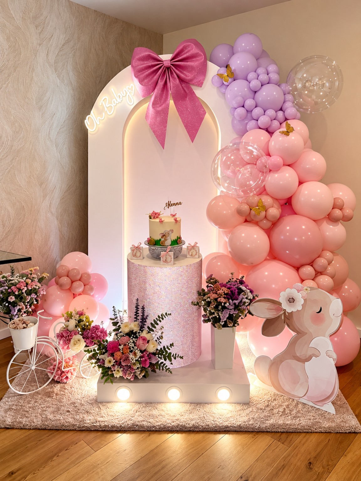 Decoração de festa com arco de balões rosa e lilás, bolo e flores